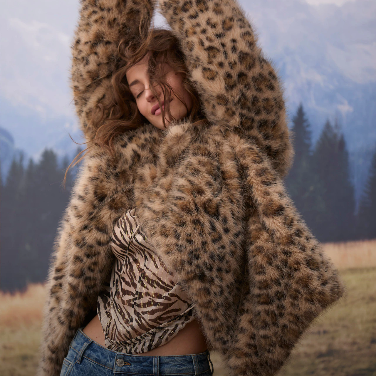 The model is wearing a striking leopard-print jacket over a zebra-print top and blue jeans.