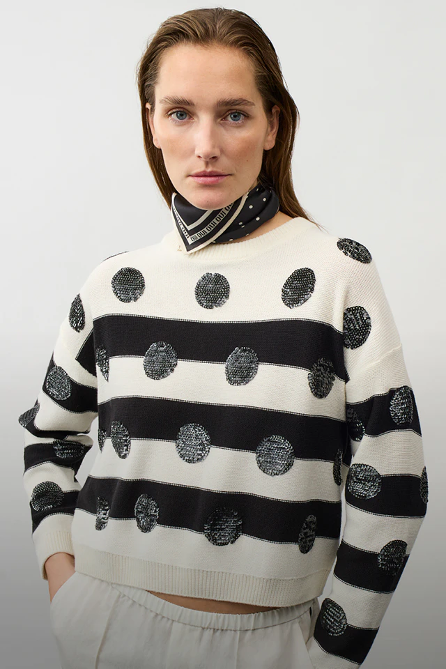 Frau mit einem schwarz weiss gestreiften Pullover mit schwarzen Pailetten Punkten und einem Halstuch in schwarz-weiss.