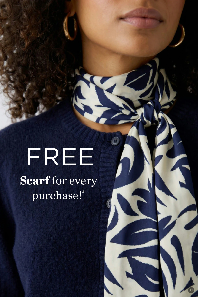 The model is wearing a dark blue knitted jumper and a cream-coloured scarf with a blue pattern.