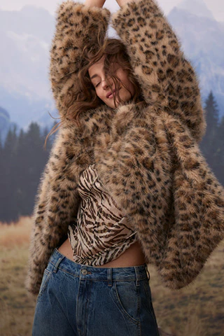 Model trägt eine auffällige Leo-Jacke über einem gemusterten Zebra-Top und einer blauen Jeans.