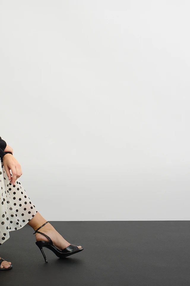 Model trägt schwarz-weiß gepunktetes Maxikleid mit schwarzem Pullover