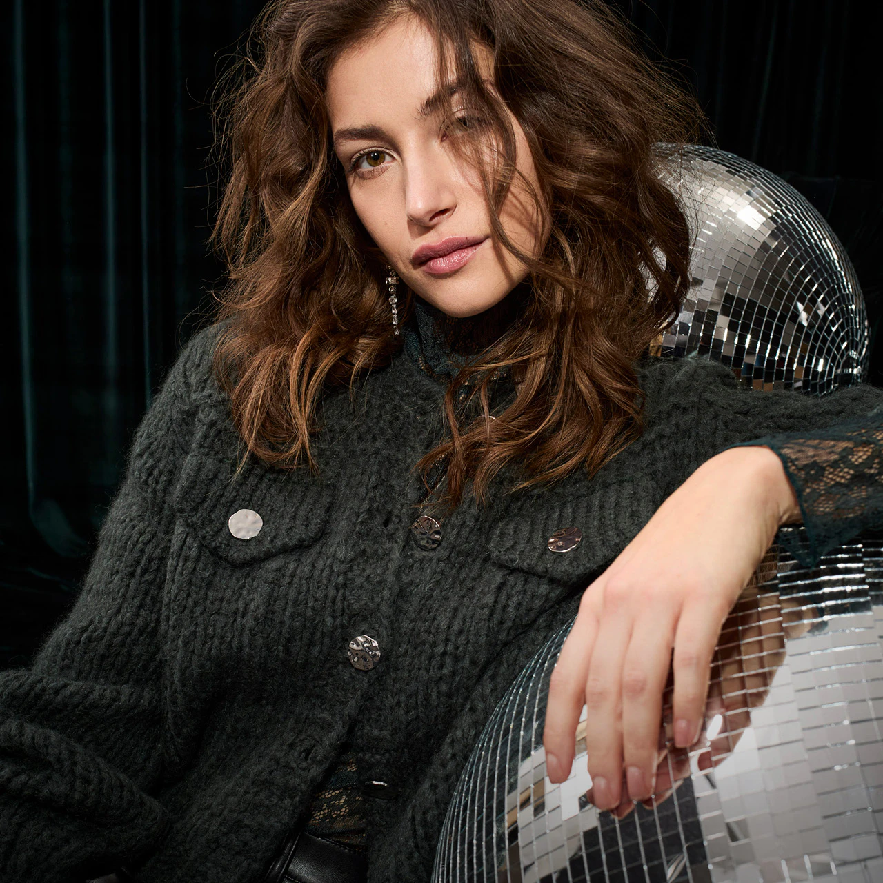 A dark green cardigan with a lace blouse and black leather trousers