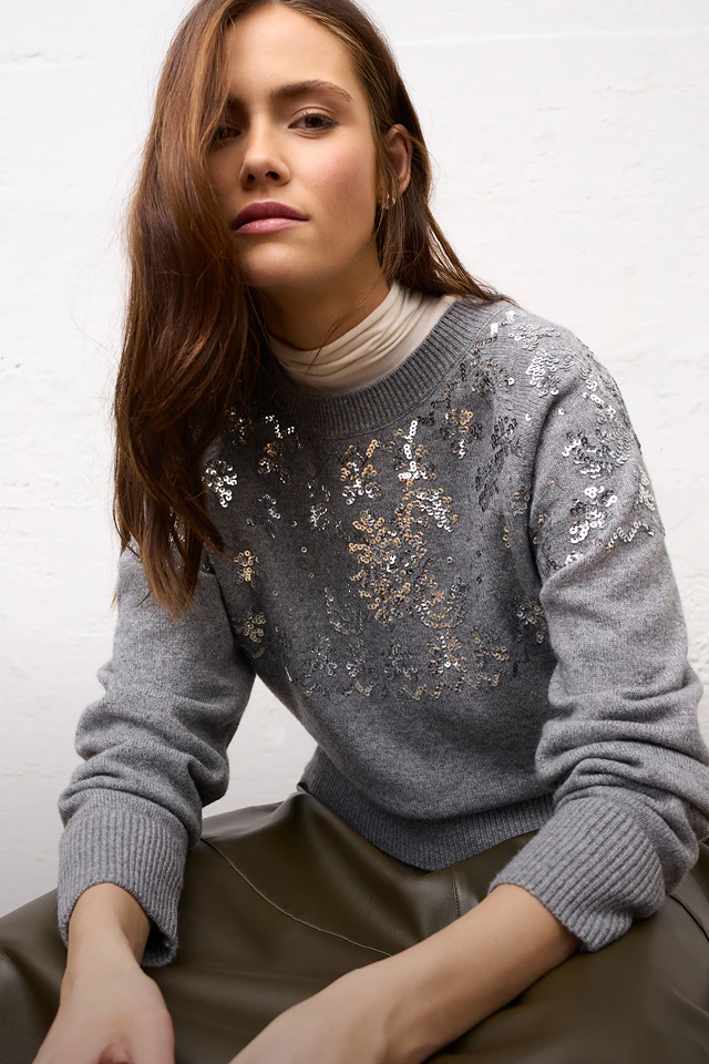 Women’s fashion from Oui, featuring a grey knitted jumper with glitter, worn over a white turtleneck top and matching trousers.