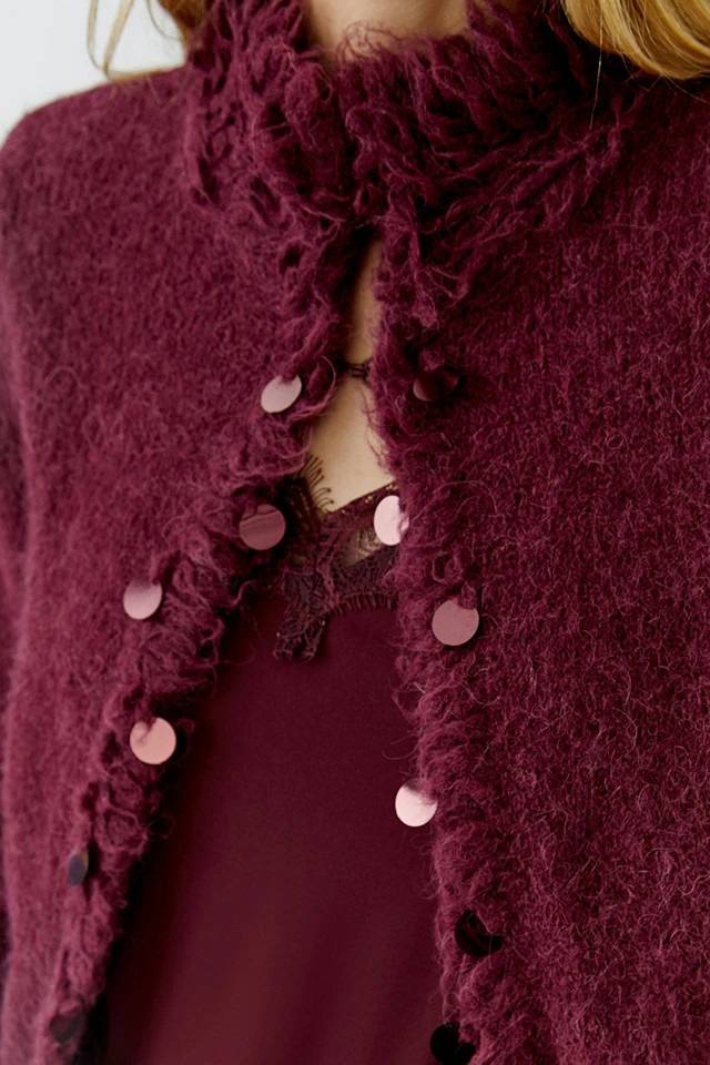 Nahaufnahme auf eine Strickjacke und ein Top in Bordeauxrot.