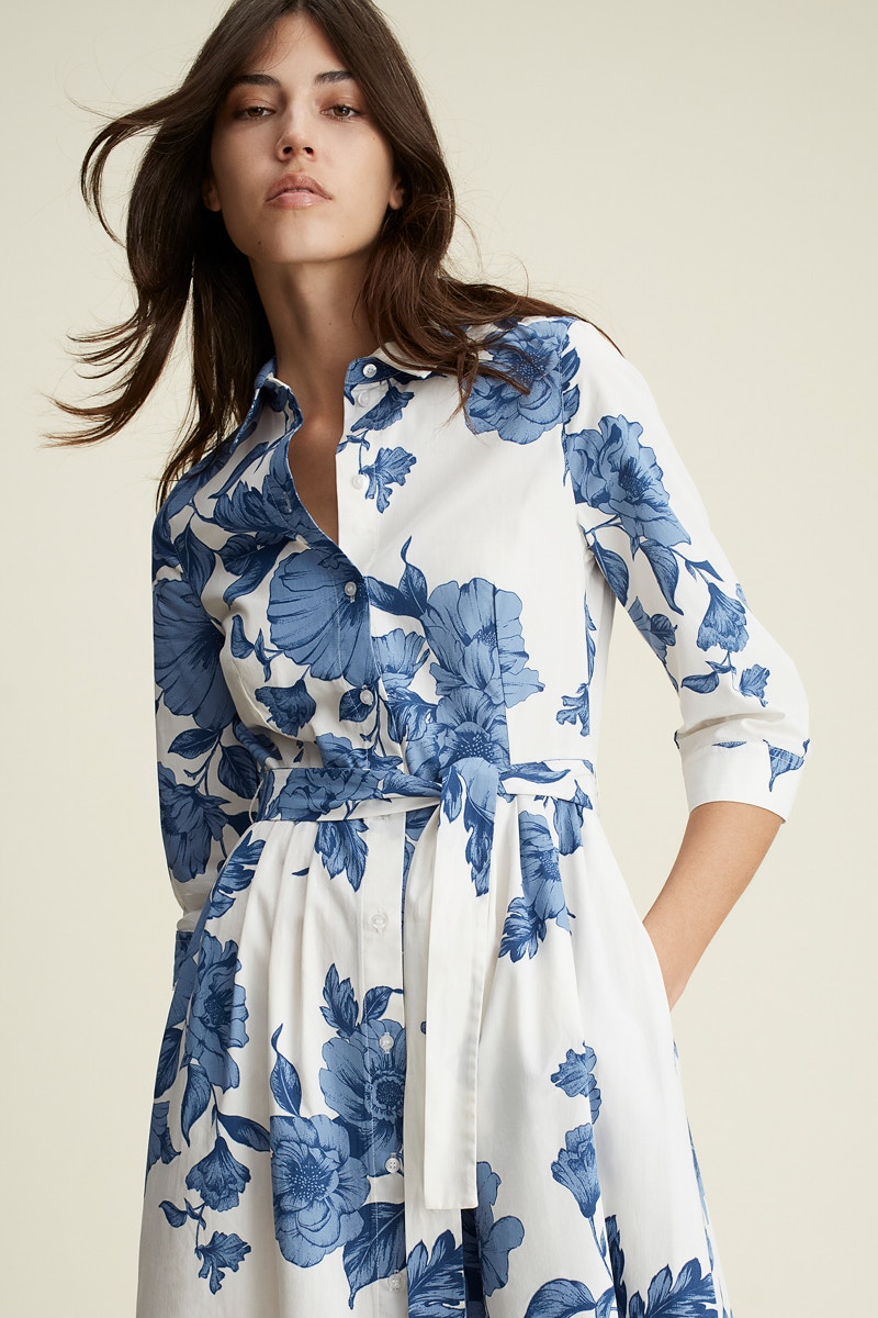 Frau trägt ein Kleid mit blauen Blumendruck auf weiß.