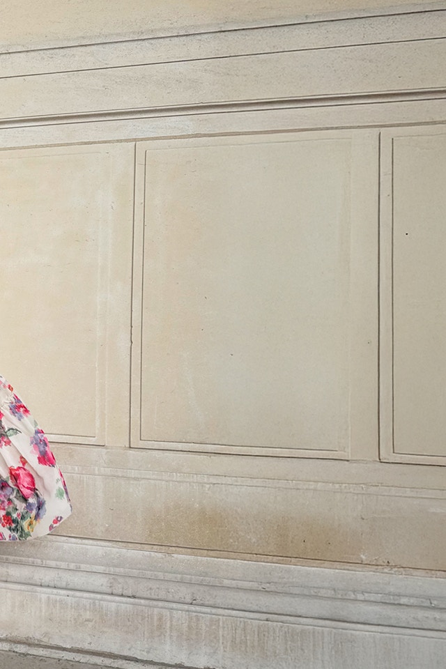 Lena is wearing a sleeveless maxi dress with a white base colour and a beautiful floral print in pink.