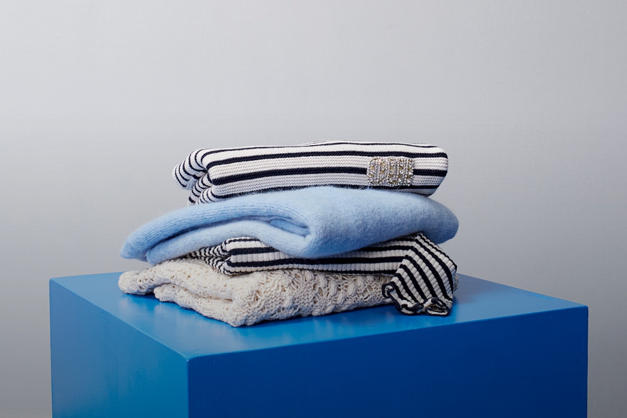 Blauer Würfel mit gefalteten Pullovern in der Farbstellung blau in uni-farben und auch gemustert.