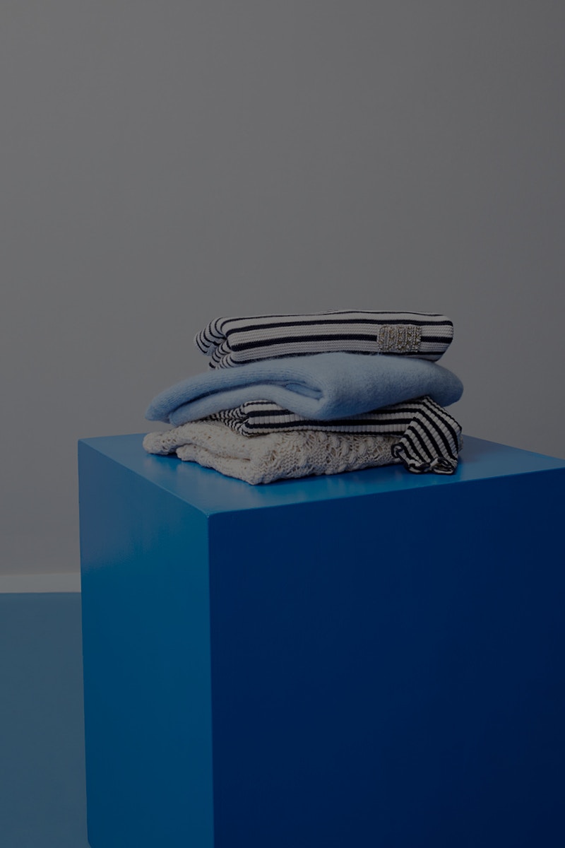 Blue cube with folded pullovers in the colour blue in plain colours and also patterned.