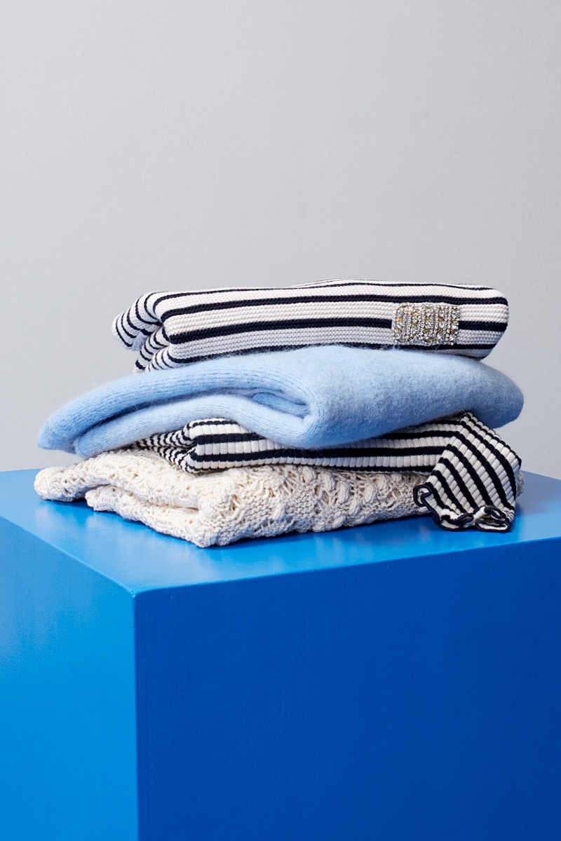 Blue cube with folded pullovers in the colour blue in plain colours and also patterned.