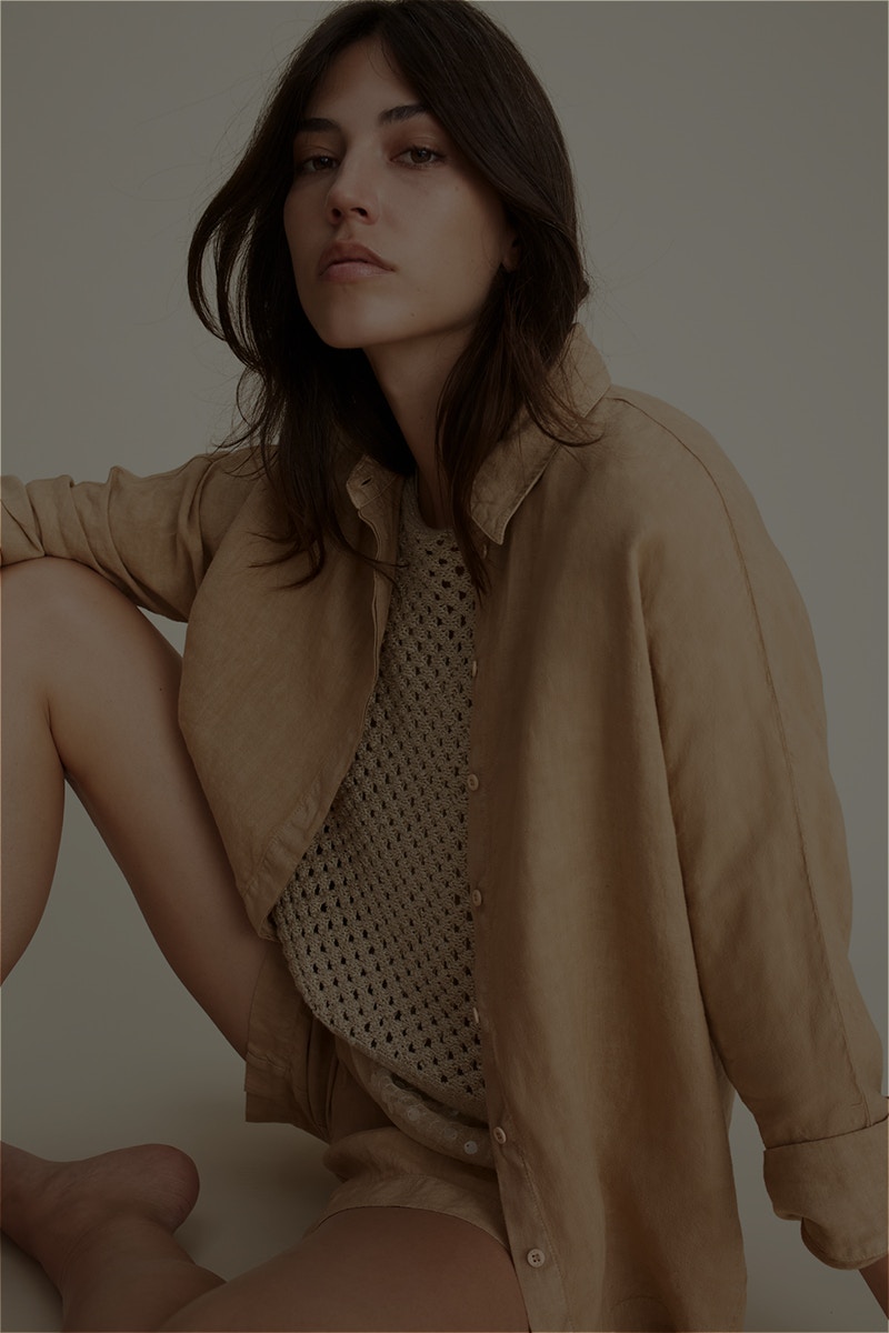 Woman wearing a brown blouse and matching shorts with a beige knitted top.