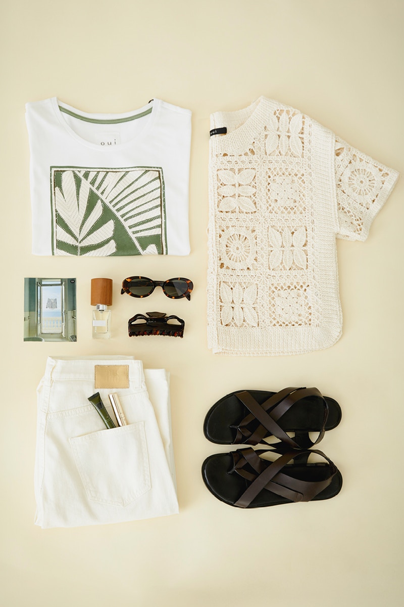 Layering picture with a white shirt with a green print with palm trees on the top left and a crocheted top in white on the right. Underneath black sandals and on the left a pair of folded white jeans.