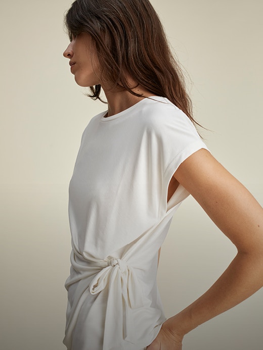 Frau mit weißem Kleid mit knotendetail an der Tailie.
