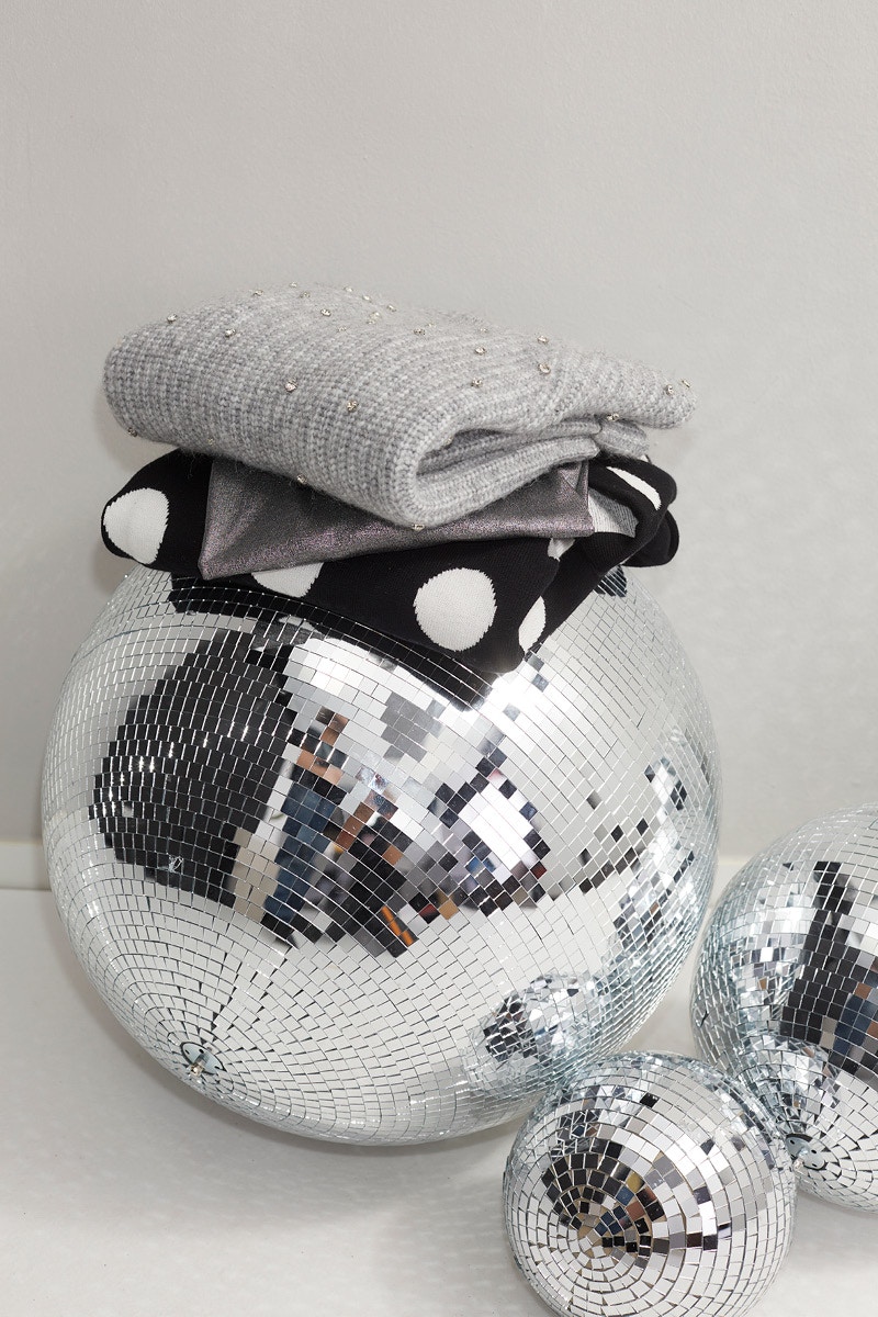 Silberne Diskokugeln mit gestrickten Pullovern gestapelt verhelfen hier eine festliche Stimmung zu erzeugen. Das Bild dient im Themenshop Modern Muse dazu die festliche Stimmung zu unterstreichen