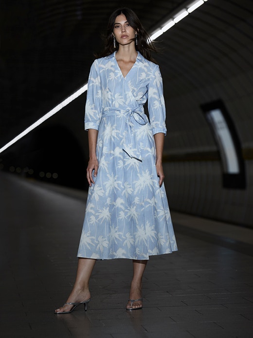 Woman wearing a midi dress in white with a light blue floral print.