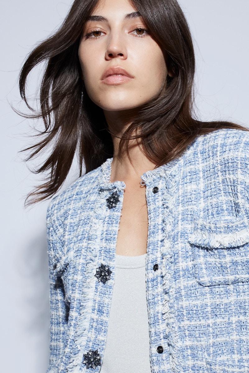 Woman wearing a light blue chequered jacket with a white top underneath.
