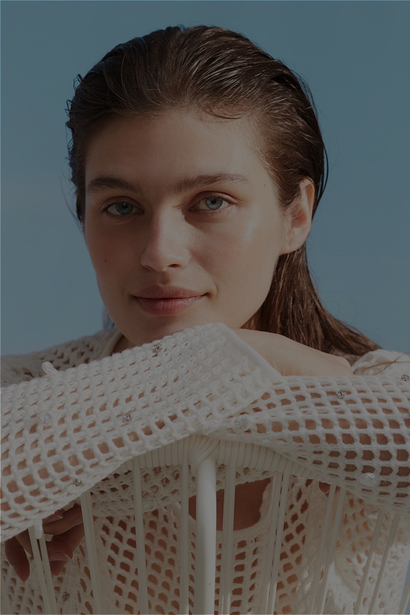 Frau mit einem weißen luftig gestrickten Pullover mit Glitzerelementen.