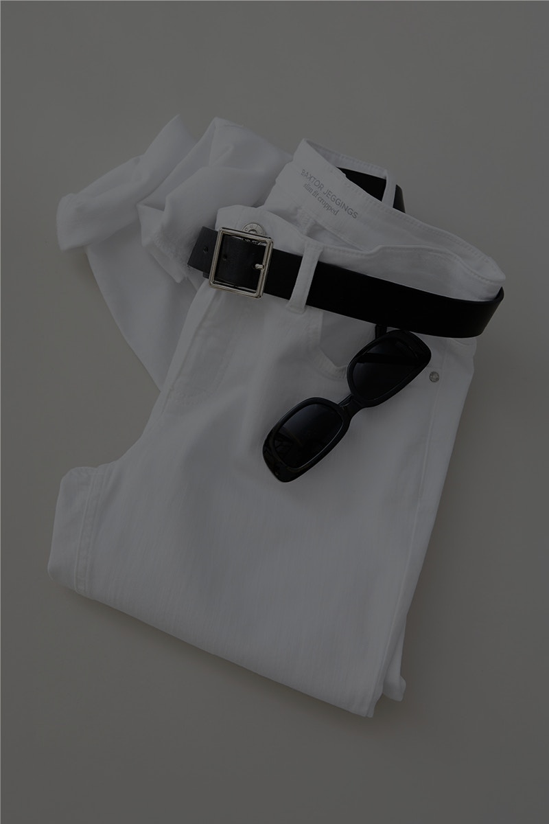 Ein Bild von oben auf eine gefaltete weiße Jeans geschootet mit einem schwarzen Gürtel und einer Sonnenbrille. Es referiert auf die Oui Essentials Baxtor Hose.