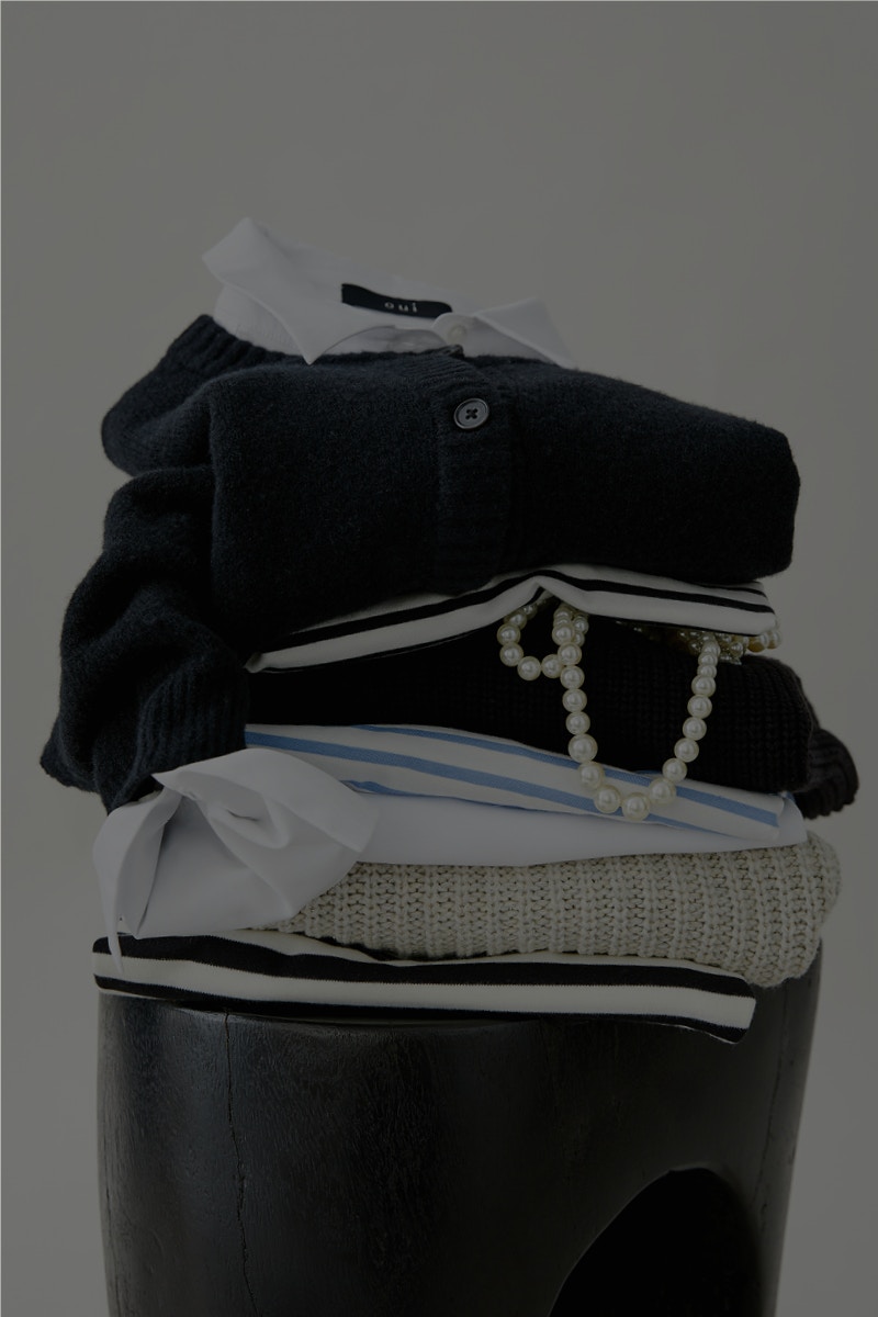 A pile of clothes on a stool, the colour variety of Oui Essentials is pointed out.