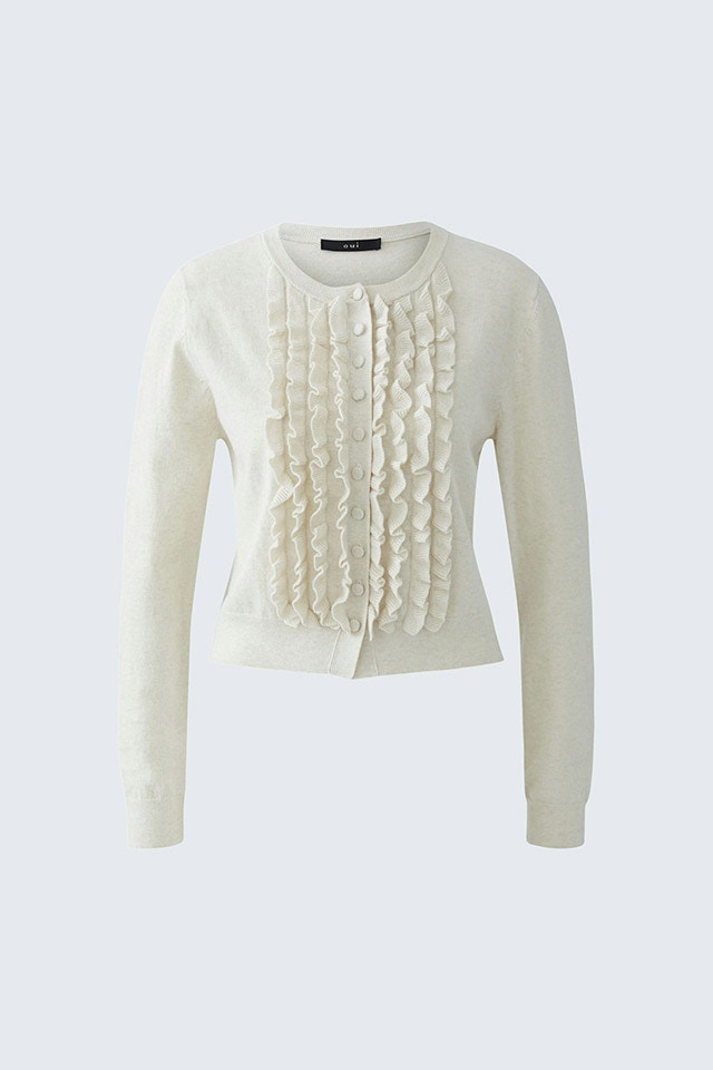 Eine weisse Strickjacke mit Rüschen.
