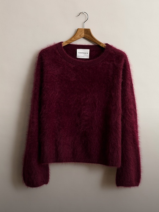 A plush burgundy jumper on wooden hangers photographed from the front.