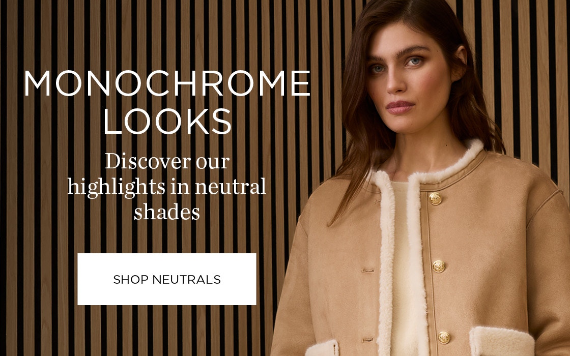 A woman on the right wearing a beige jacket with white fluffy edges and gold decorative buttons, wearing a cream-coloured jumper underneath. Font on the left: Monochrome Looks - Discover our highlights in neutral shades and a click area: Shop Neutrals.