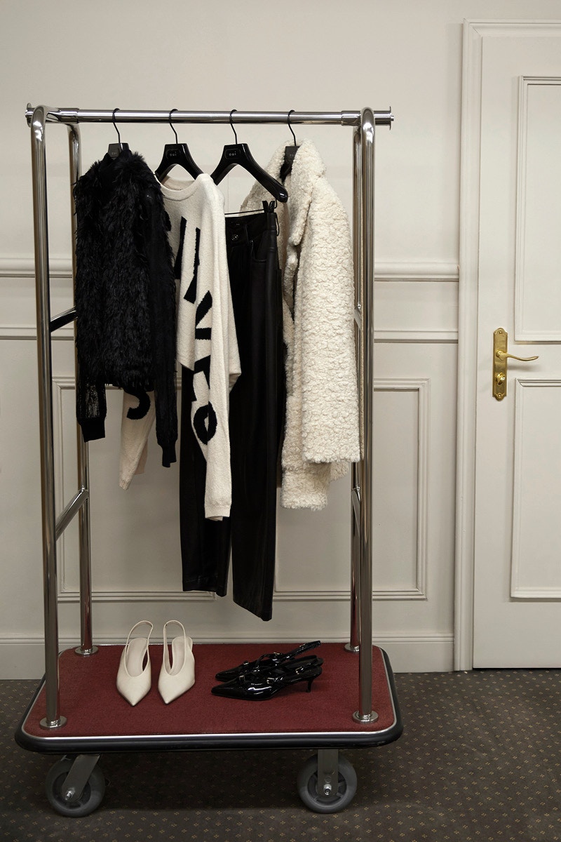 A rack of clothes on hangers, black sequinned jacket, white patterned shirt, black trousers and white jacket.