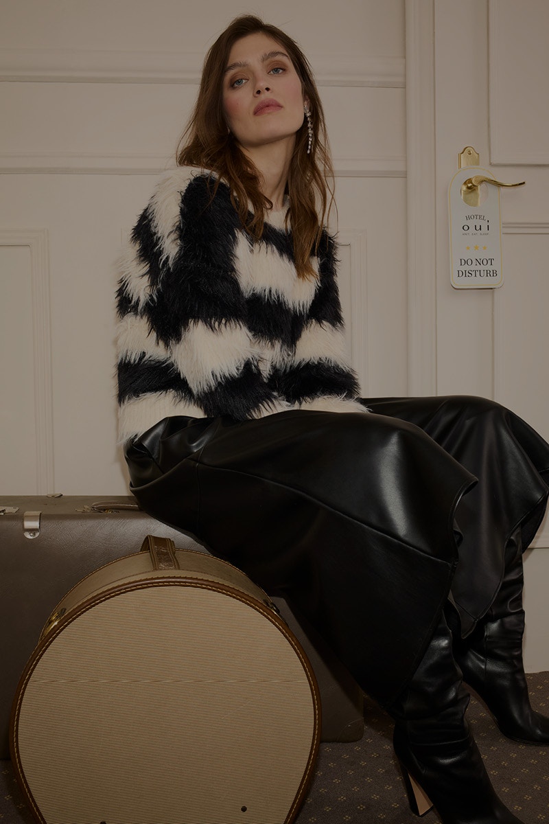 Woman with black and white striped jumper and black leather-look skirt.
