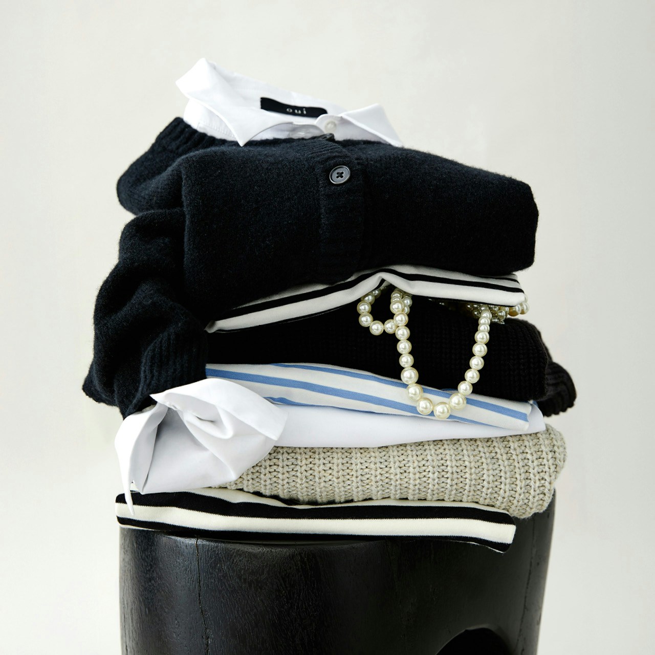 A pile of clothes on a stool, the colour variety of Oui Essentials is pointed out.