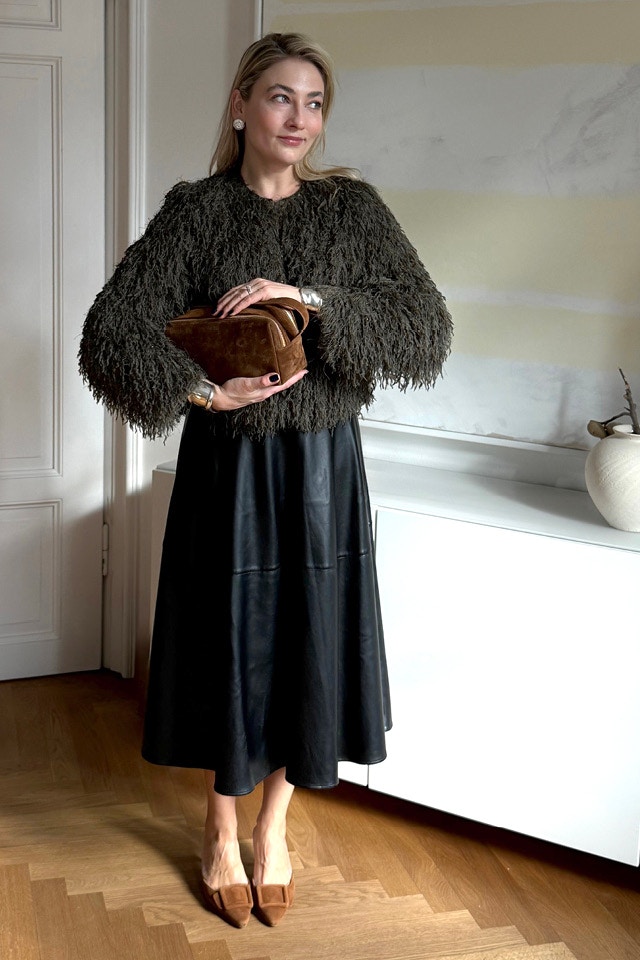 Influencerin Oleysa Schuler traegt eine Fransenstrickjacke in dunkelgruen und dazu einen passenden Rock in schwarz in Lederoptik.