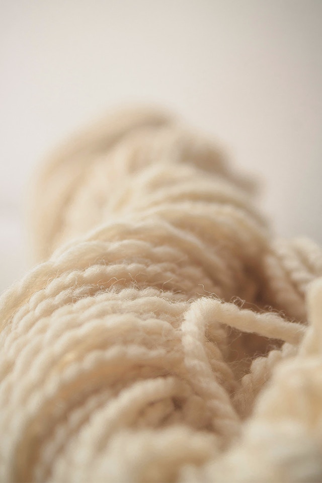 Ein beiges Wollgarn ist auf dem Bild zu sehen.