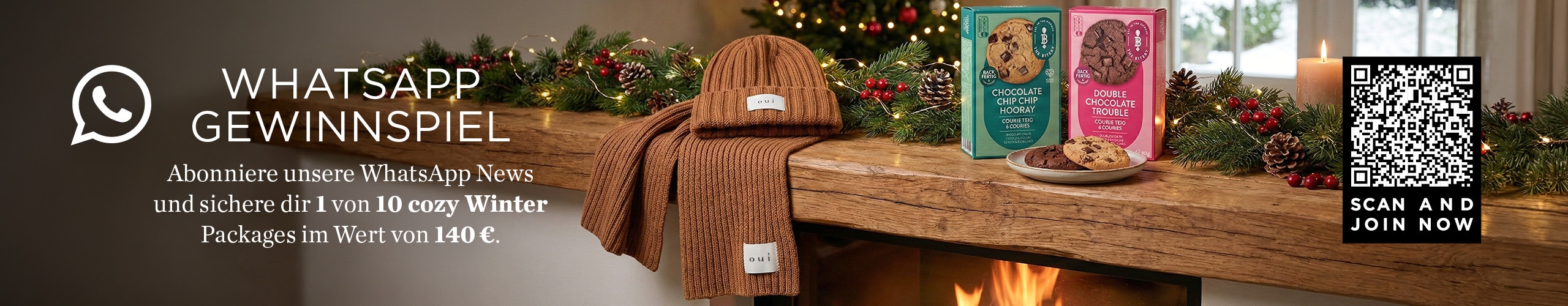 Holztisch mit einem Schal und Mützenset in braun, 2 Kekspackungen. Verwiesen wird auf ein Gewinnspiel in WhatsApp.