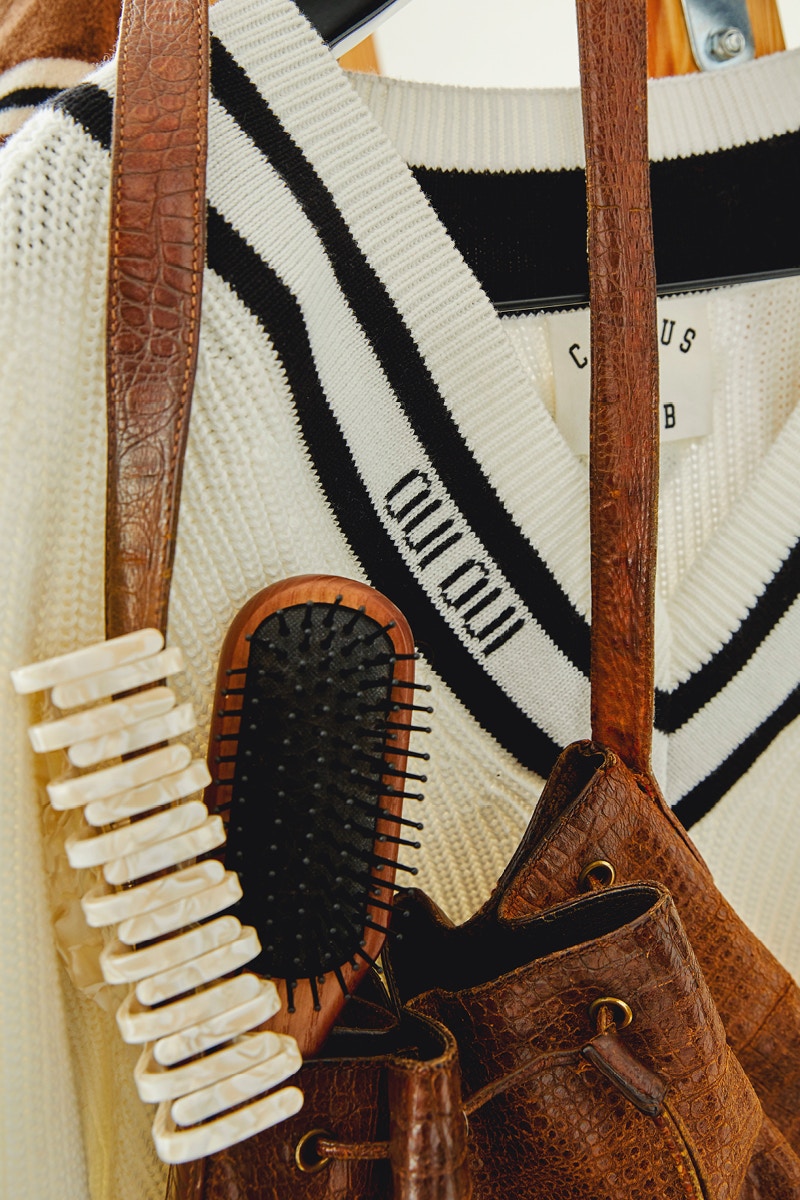 Ein beiger Pullover gehängt auf einem Kleiderbügel mit V-Ausschnitt mit braunem Kontrast am Kragen.