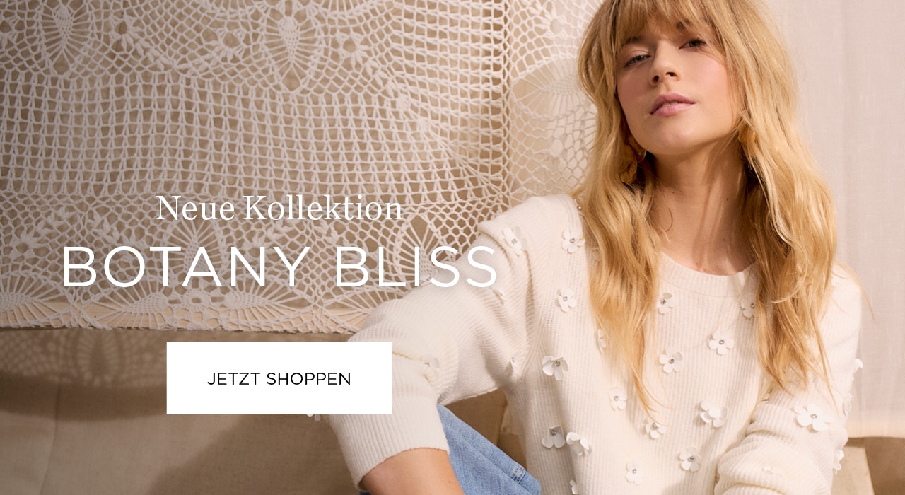 Frau mit weißem Pullover mit Blüten und Jeanshose. Text: Neue Kollektion: Botany Bliss mit Klickfläche jetzt shoppen.