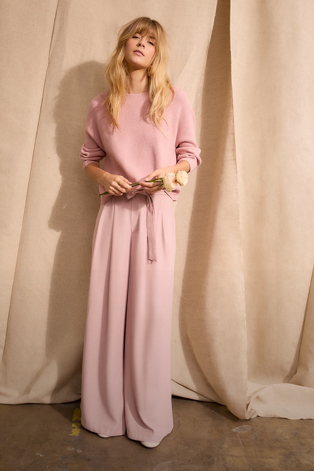 Woman in a total pink look with jumper and trousers.