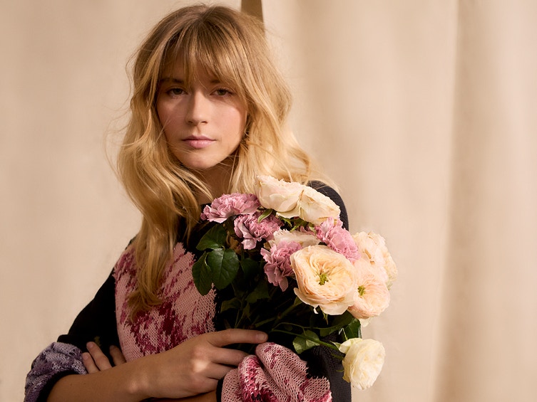 Frau mit schwarzem Pullover mit farbenfrohen Blumendruck.