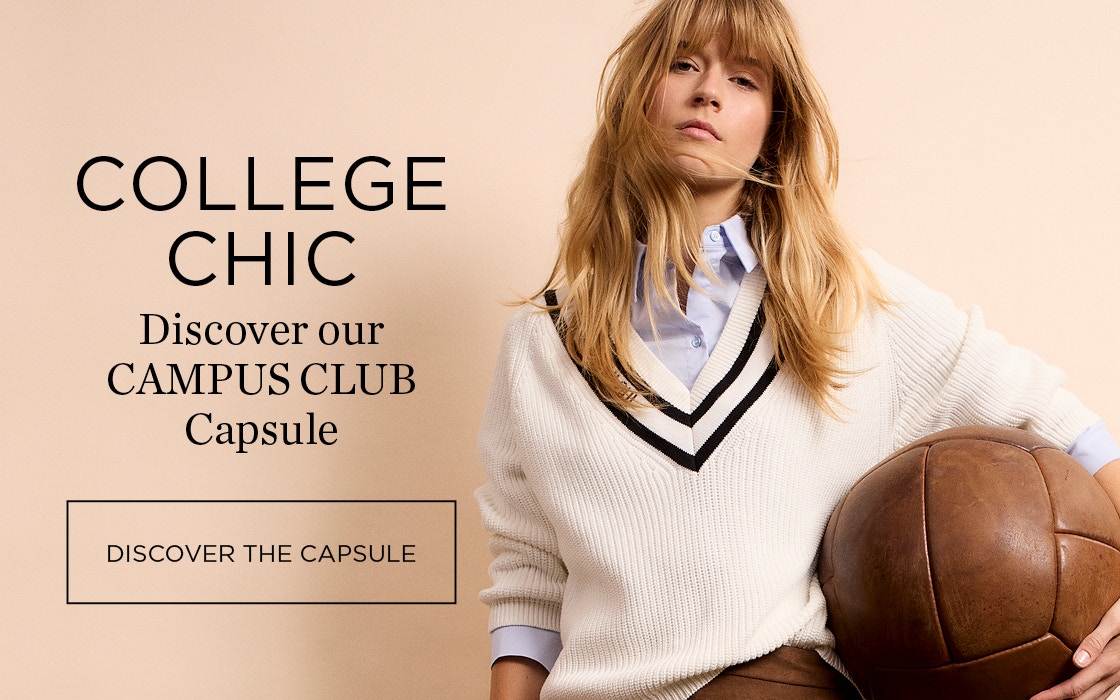 Woman wearing a beige jumper with a brown V-neck and a brown skirt.