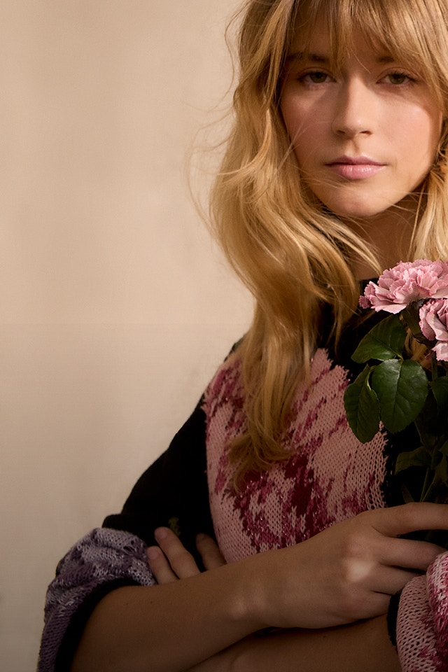 Frau mit schwarzem Pullover mit farbenfrohen Blumendruck.