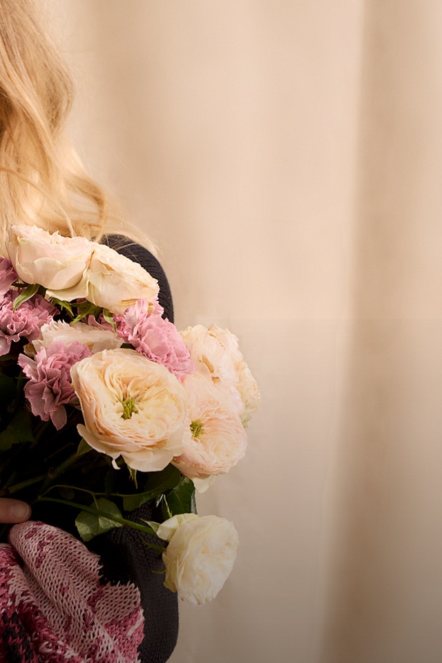 Frau mit schwarzem Pullover mit farbenfrohen Blumendruck.