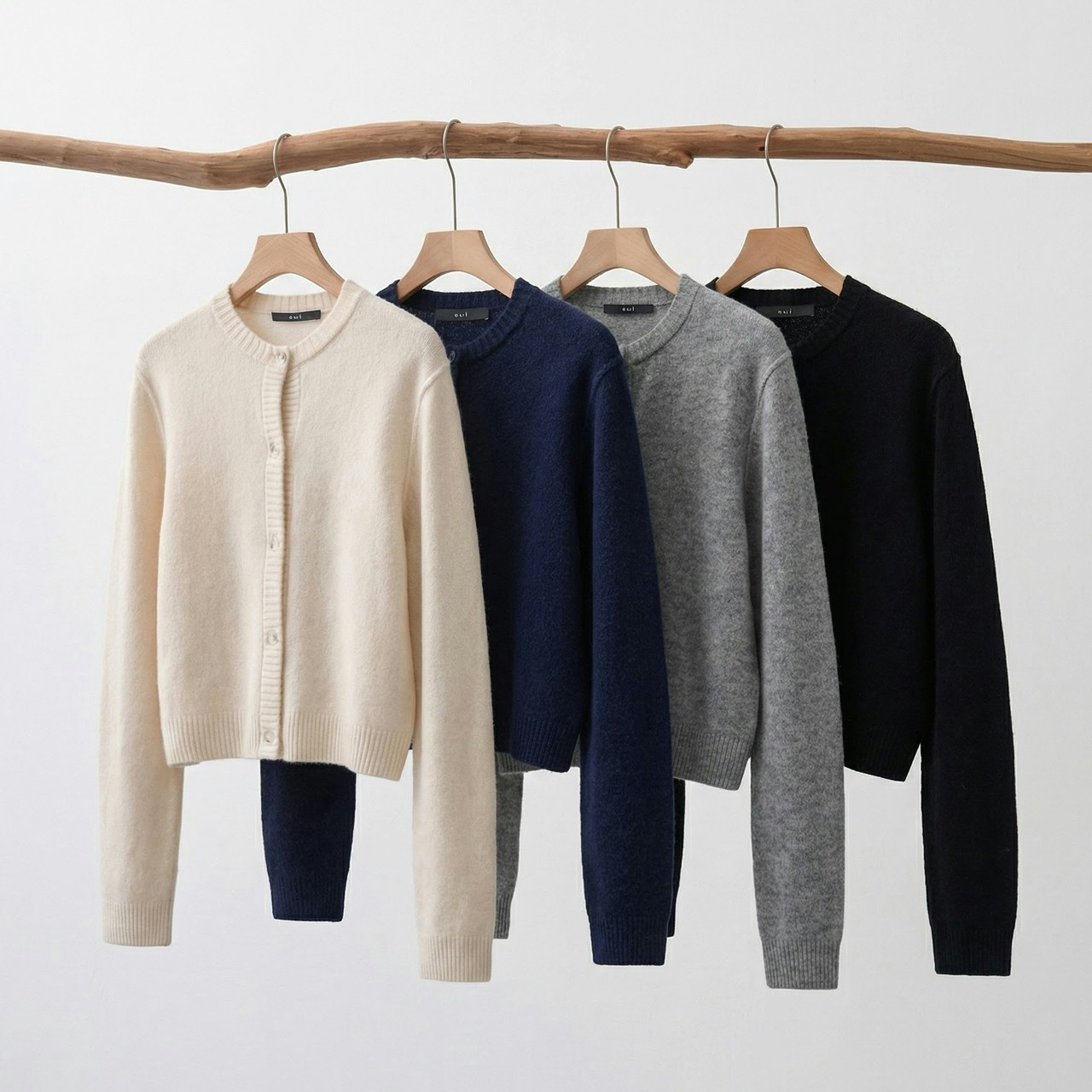 4 Strickjacken ILYA in beige, blau, grau und schwarz hängend auf Bügeln.