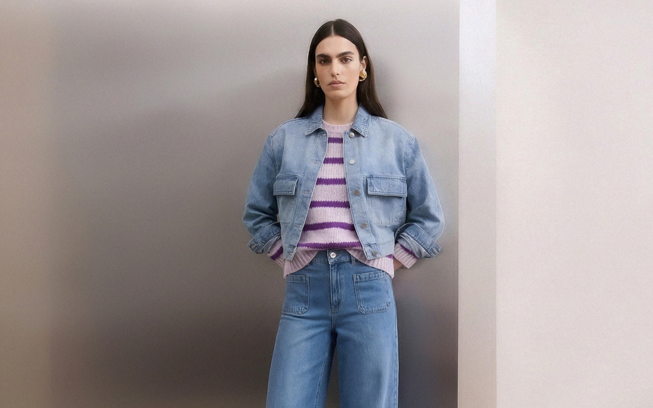 Woman wearing a denim jacket, striped jumper in purple and lilac with jeans.