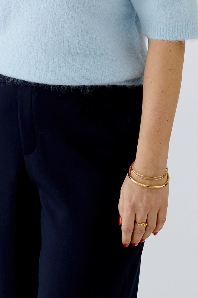 Close-up of a torso wearing a light blue jumper and dark blue trousers.