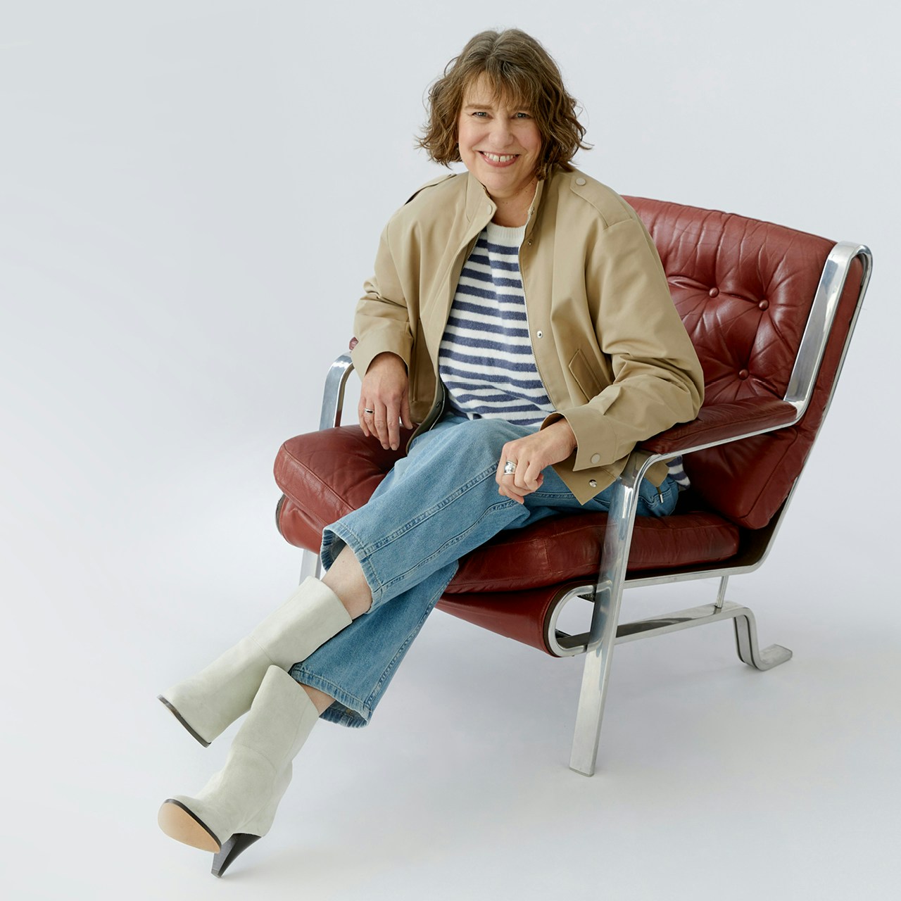 Kerstin is wearing a beige jacket with a blue and white striped jumper and jeans.