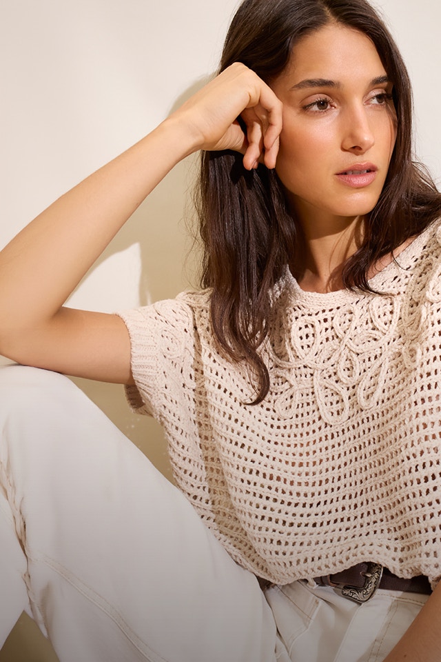 Woman wearing a beige crocheted short-sleeved jumper.