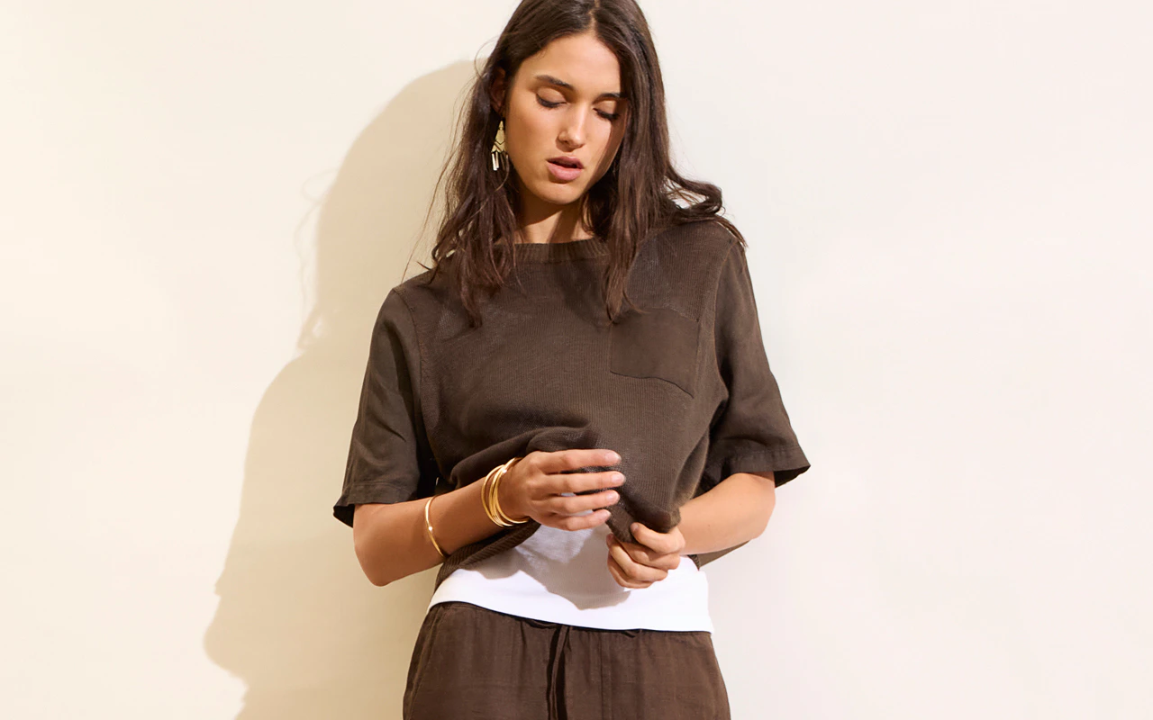The model is wearing a dark brown linen set and a white top