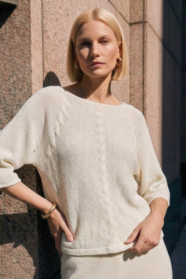 Frau mit einem beigen Pullover und beiger Hose.