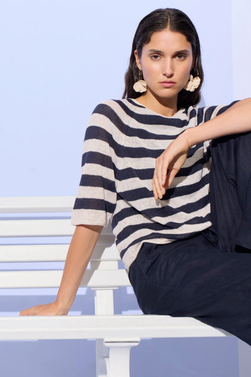 Frau mit einem kurzarm Pullover in blau-weiss gestreift und einer blauen Hose.