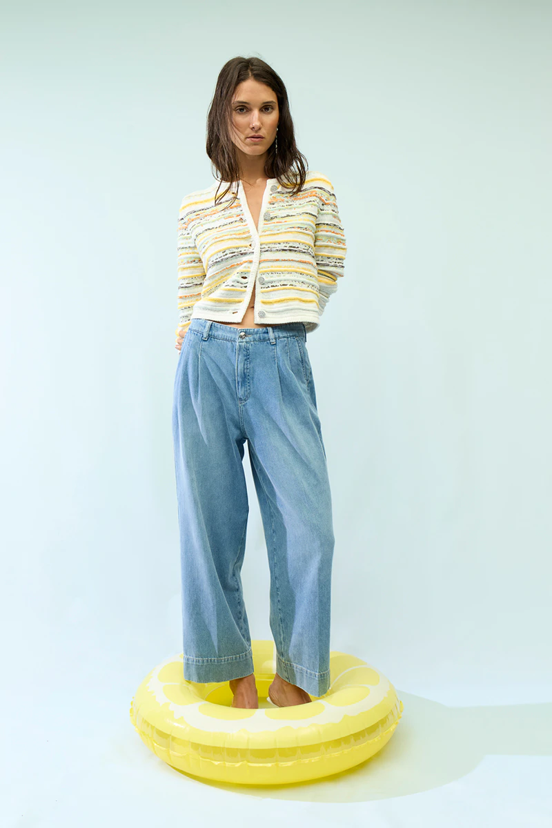 Frau trägt eine bunt gestreifte Strickjacke und eine lässige Jeans.