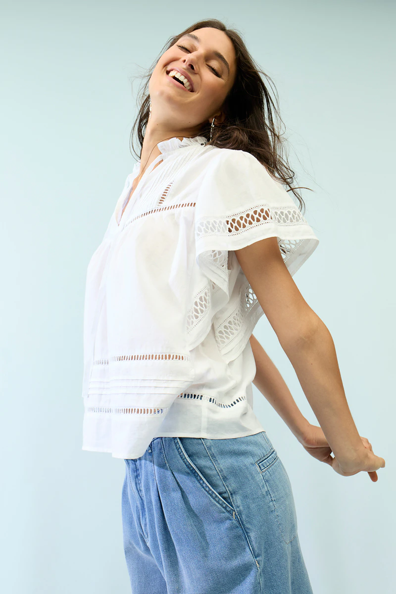 The woman is wearing a white blouse and jeans.