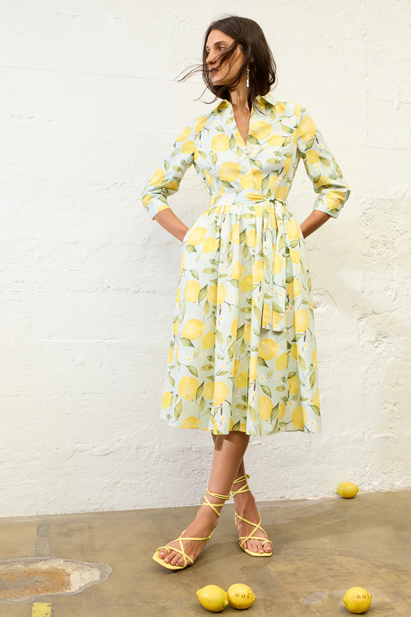 A woman is wearing a dress with a lemon print.