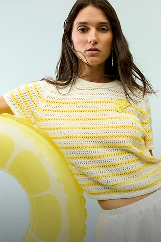 The woman is wearing a yellow and white striped short-sleeved jumper and a white skirt.
